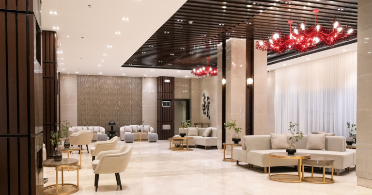 Red Residences' lobby featuring sleek modern design with vibrant red accents, polished marble floors, contemporary furniture, and soft ambient lighting creating an inviting atmosphere.