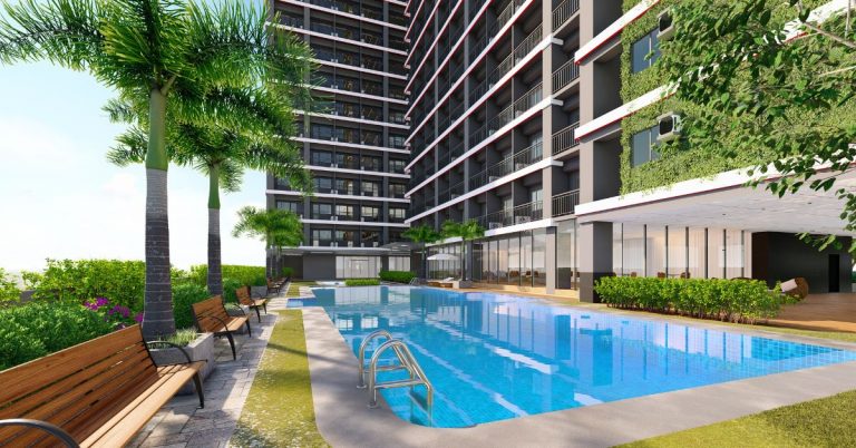 An inviting view of the amenity pool at Red Residences, featuring sparkling turquoise water bordered by lush landscaping and sun loungers, providing residents with a refreshing oasis to relax and unwind.